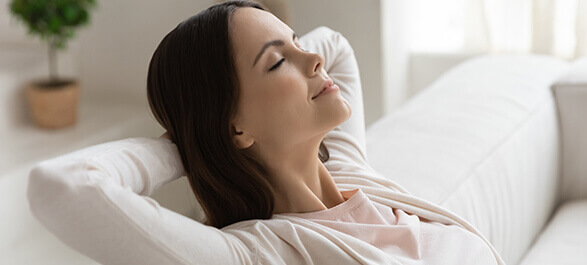 A woman relaxing in her home, enjoying fresh, clean air thanks to effective air quality testing, HVAC system maintenance, and proper heating and cooling. Professional AC repair and ductwork services ensure a comfortable living environment with optimal air quality.