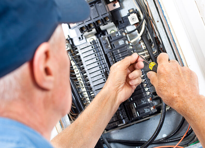 An experienced electrician performing DIY electrical installation with a power tool while working on electrical repairs, including wiring and lighting installations. The image emphasizes expertise in home electrical services, HVAC systems, aeroseal duct sealing, AC repair, and furnace replacement, ideal for showcasing the skills required for electrical and HVAC maintenance in residential spaces.