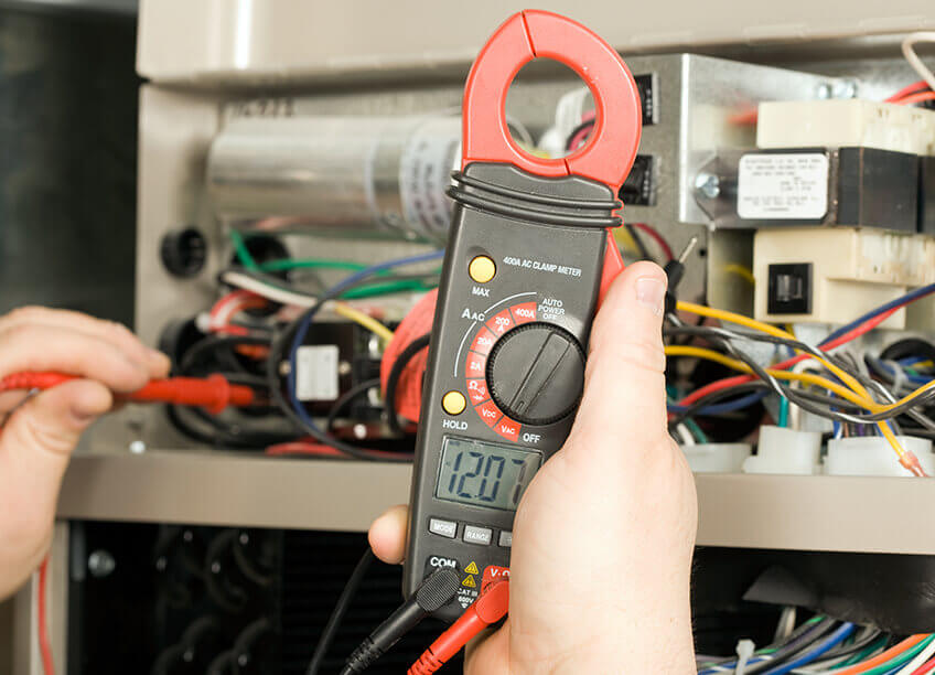 A woman shivering in cold while adjusting the thermostat, waiting for the heating and cooling system to kick in. This highlights the importance of professional HVAC services, including furnace repair, furnace replacement, and boiler repair. The image emphasizes energy efficiency through aeroseal duct sealing, ensuring optimal comfort. An electrician may be required to handle any wiring issues while providing services such as air quality testing, heating, and cooling system repairs, including advanced solutions for ductwork, thermostat issues, and ensuring proper HVAC system functionality.