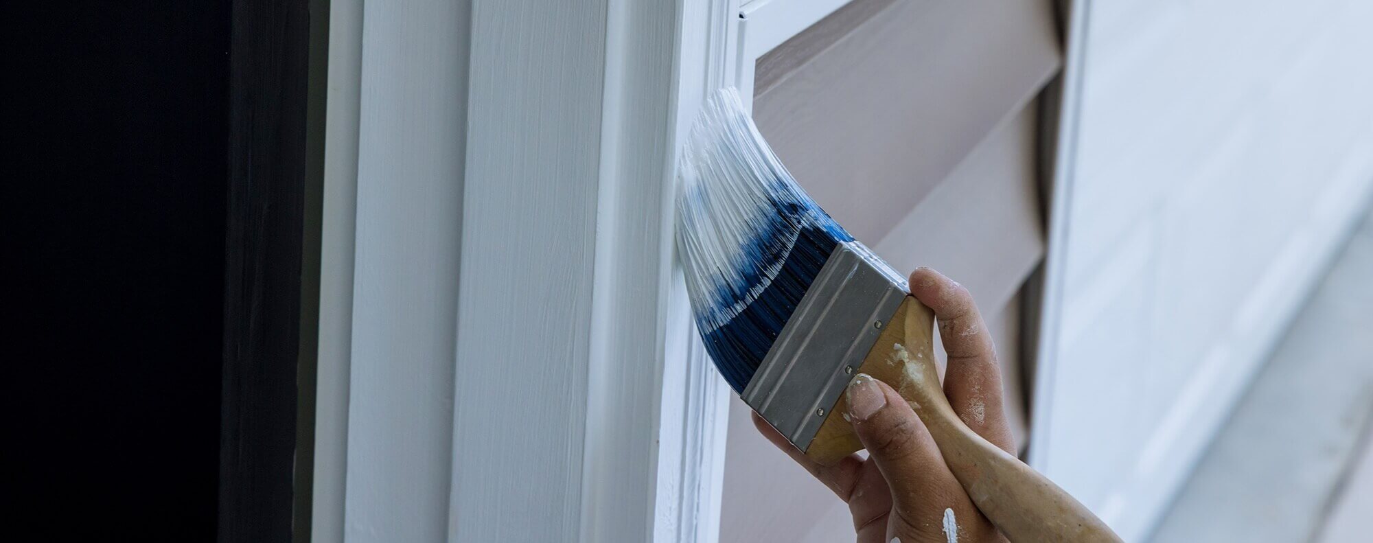 A person painting the trim of a house exterior, representing home maintenance services like painting, which is part of comprehensive handyman services. This image complements HVAC services such as furnace replacement, HVAC installation, and air duct cleaning. Exterior painting enhances a home's curb appeal, while HVAC services ensure comfort and energy efficiency inside, making both essential for a well-maintained and comfortable home environment.