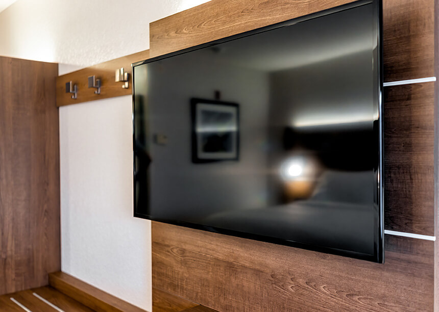 A person mounting a TV on the wall, illustrating handyman services that also include HVAC installation and repair. This image complements services such as furnace replacement, air duct cleaning, and HVAC repair. The work involved in mounting devices like TVs mirrors the skilled precision required in HVAC system installations and repairs, ensuring a comfortable, functional, and well-maintained home. This image highlights the versatility of handyman services, including both technical electrical work and home comfort systems.