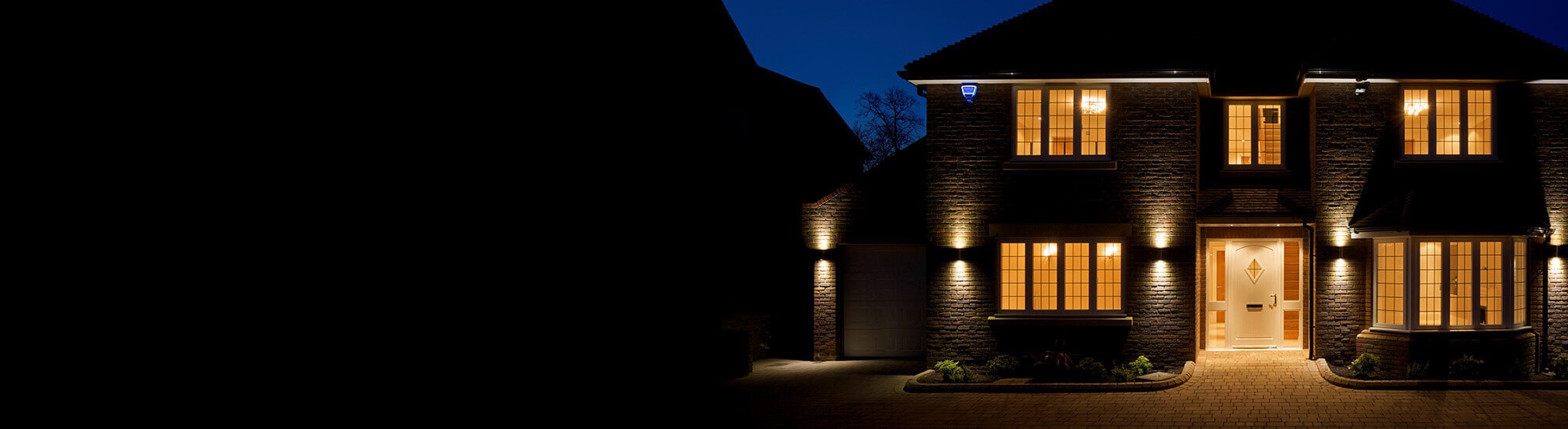 A beautiful home illuminated at night, highlighting the importance of both exterior lighting and the comfort and safety provided by HVAC services. This image showcases the professional work of electrical contractors in home security lighting, HVAC services including furnace replacement, HVAC installation, ductwork, and air quality testing to ensure a safe and comfortable environment. The home’s exterior lighting complements the importance of maintaining a well-lit and secure property while also maintaining optimal indoor air quality.